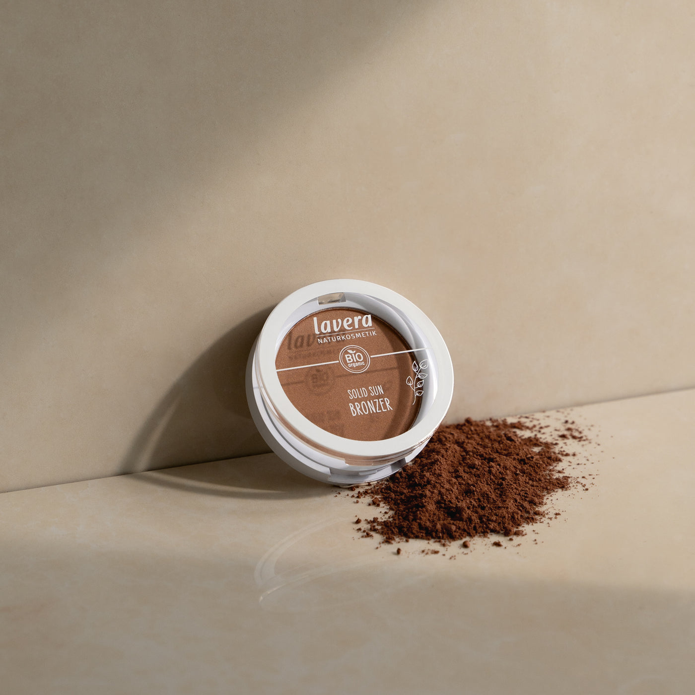 Lavera Solid Bronzer angelehnt an einer beschen Wand