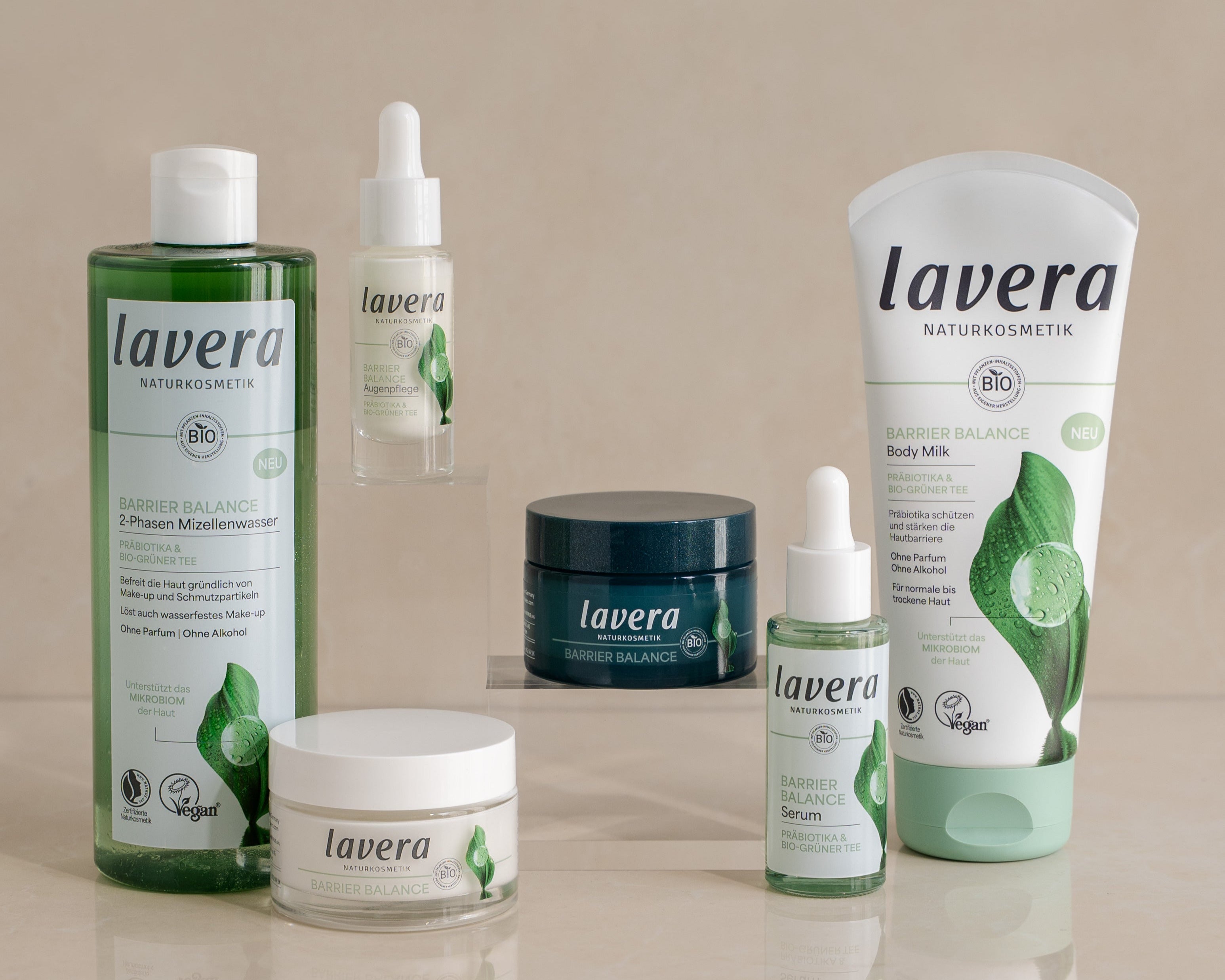 Sechs lavera Naturkosmetik Barrier Balance Produkte, darunter 2-Phasen Mizellenwasser, Augenpflege, Creme, Serum, Body Milk und eine Gesichtscreme, auf hellem Untergrund nebeneinander arrangiert.