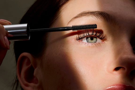Frau trägt Mascara auf ihre Wimpern auf