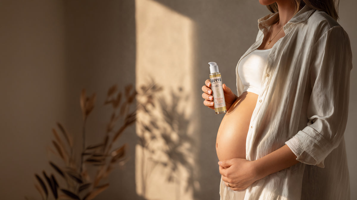 Schwangere Frau hält Mama Care Schwangerschaftsöl in der Hand