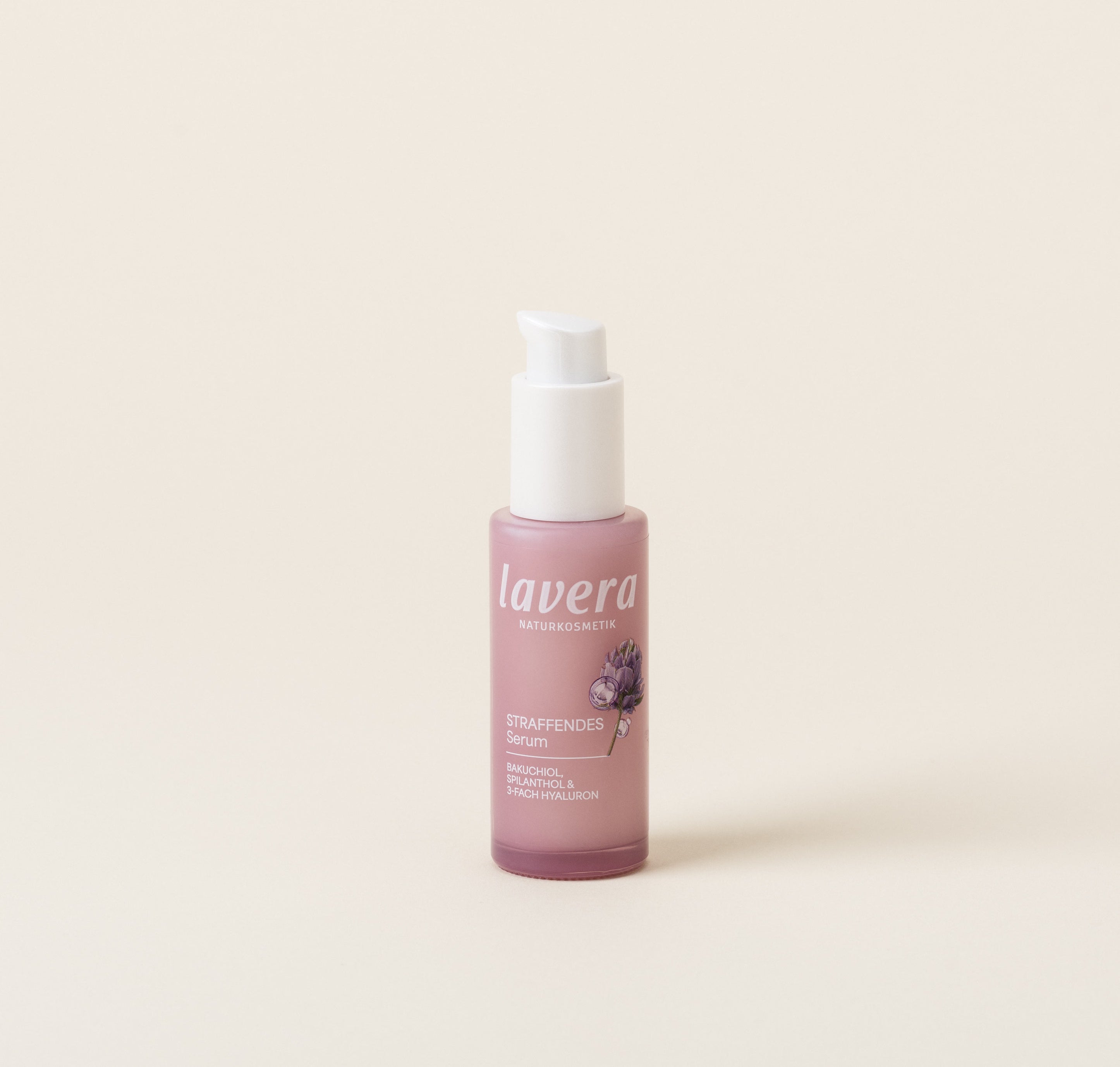 A pink bottle of lavera Firming Serum stands against a light, neutral background.