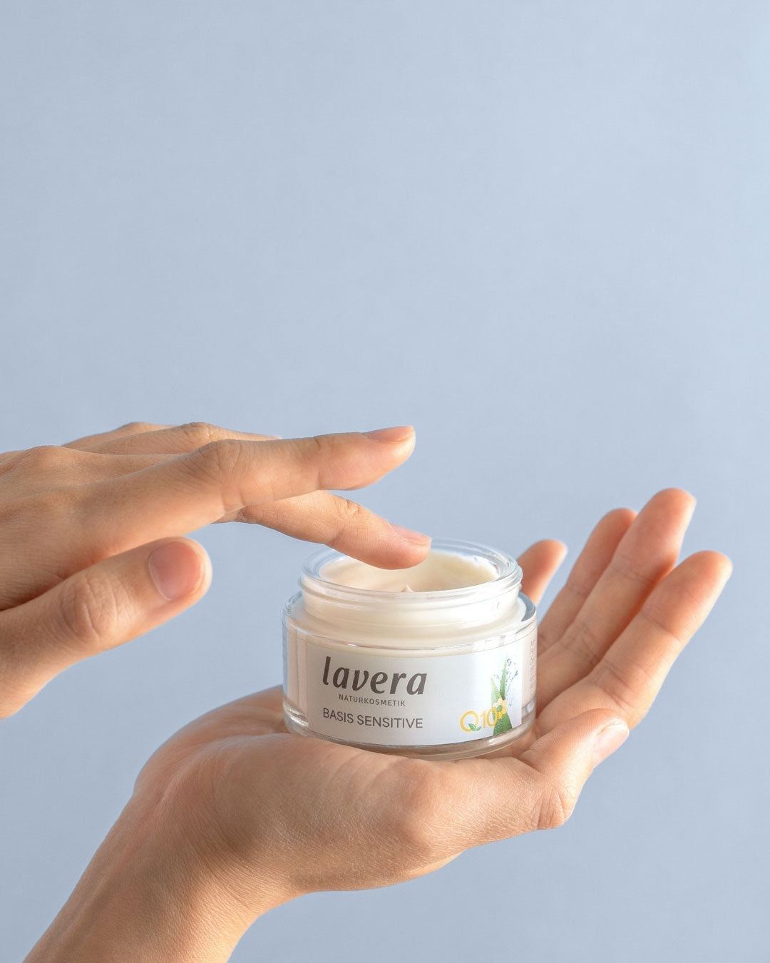 lavera basis sensitive Q10 day cream in the palm of one hand