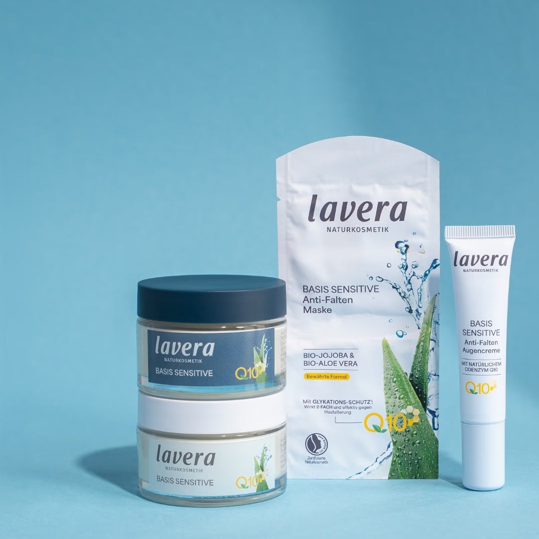 Four lavera Basis Sensitive anti-wrinkle products with Q10 stand against a light blue background: two cream jars, a sheet mask, and an eye cream.