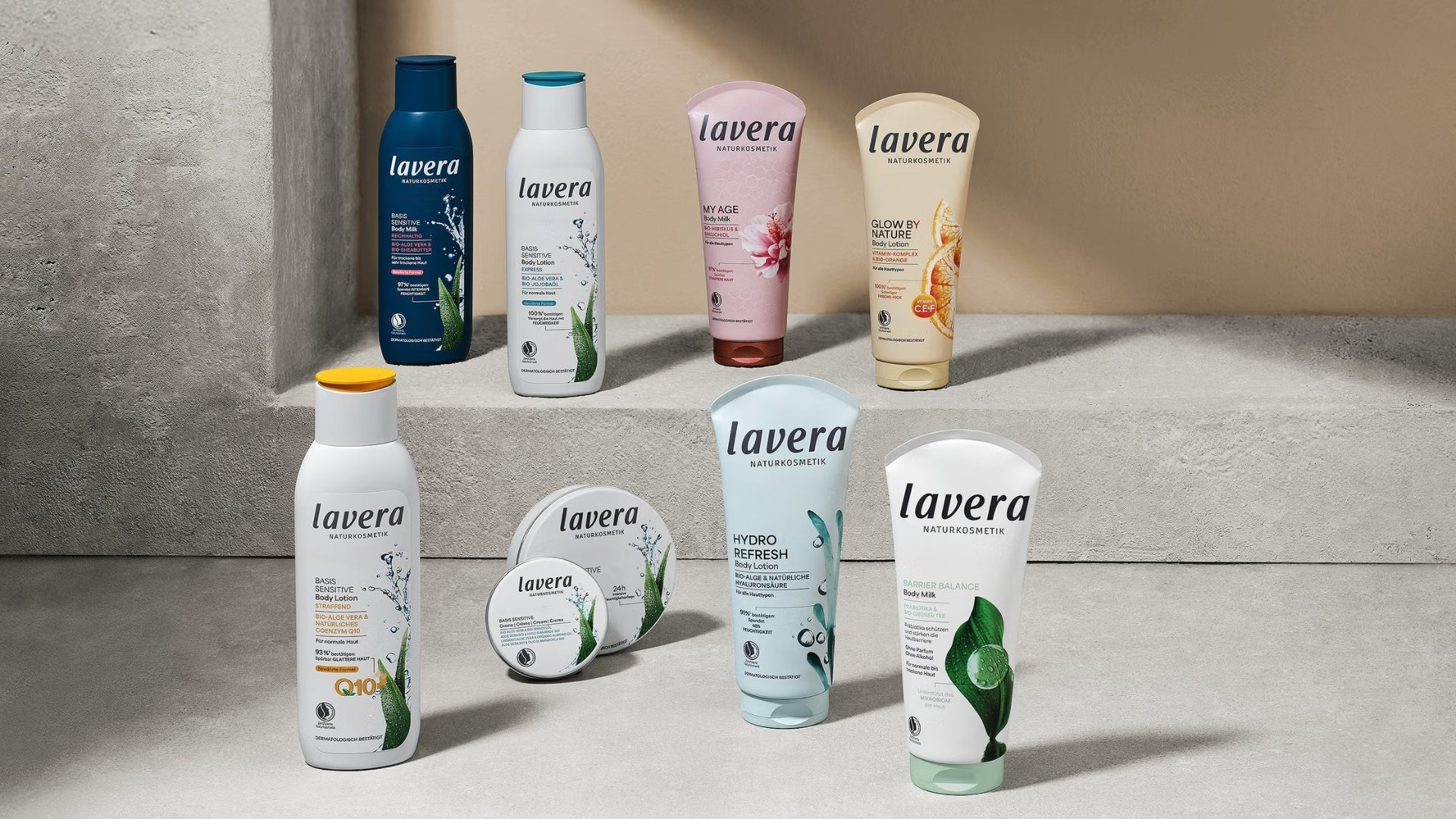 Nine lavera body care products, including lotions, body milk, and creams, standing on tiered concrete plinths in a modern, illuminated room.