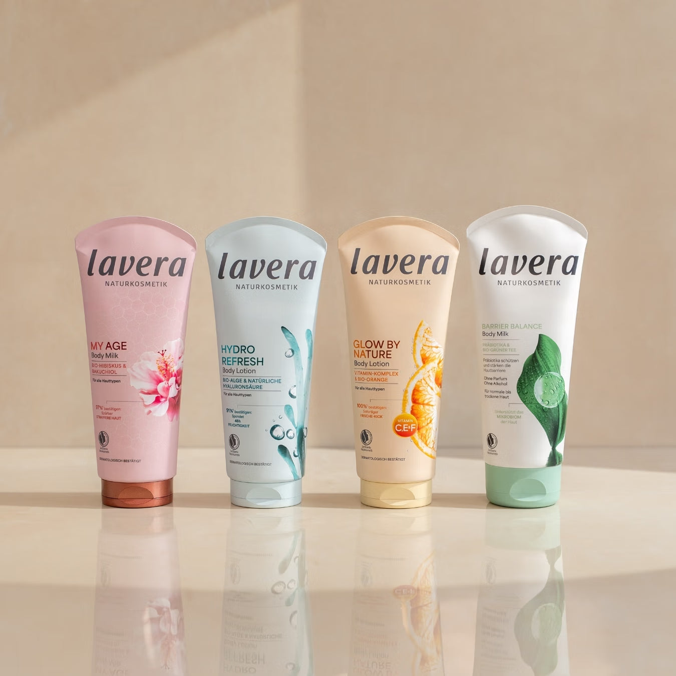 Four lavera body lotions are standing side by side on a reflective surface.