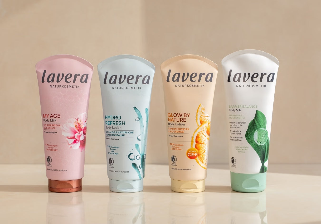 Four lavera body lotions are standing side by side on a reflective surface.