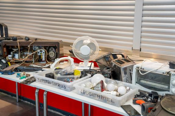 Elektroschrott auf Tisch: alte Geräte, Kabel und Boxen für Batterien & Leuchtmittel