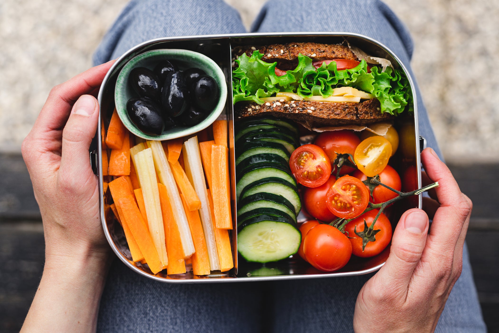 Bento-Box mit Sandwich, Karotten, Gurke, Tomaten und Oliven, Draufsicht