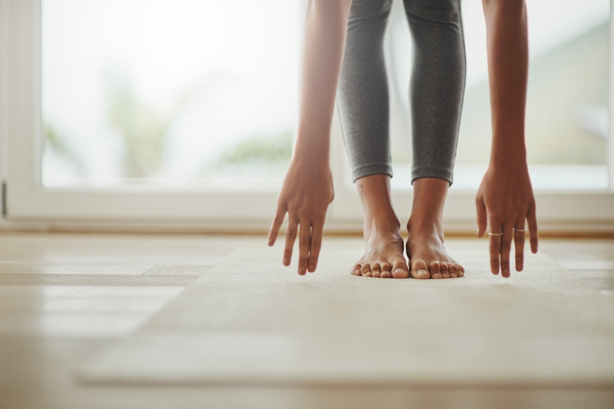 Untere Bein- und Armpartie einer Frau, die auf einer Yogamatte steht