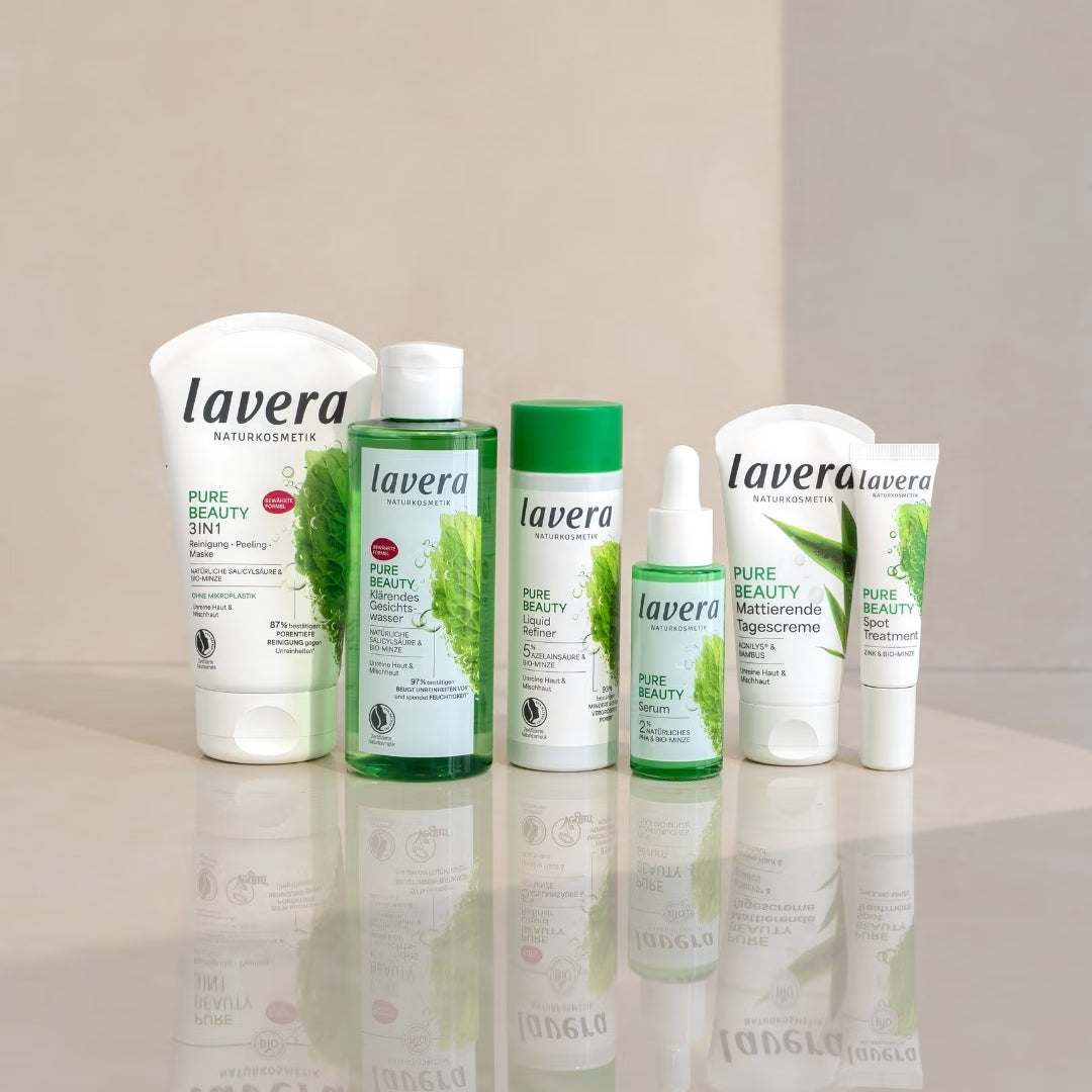 lavera Pure Beauty facial skincare products stand on a reflective surface against a bright, two-part background.
