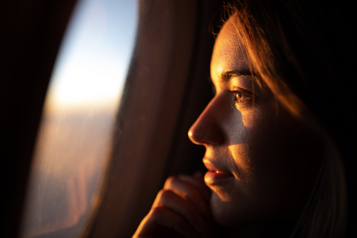 Nahaufnahme des Gesichts einer Frau, die aus dem Flugzeugfenster schaut