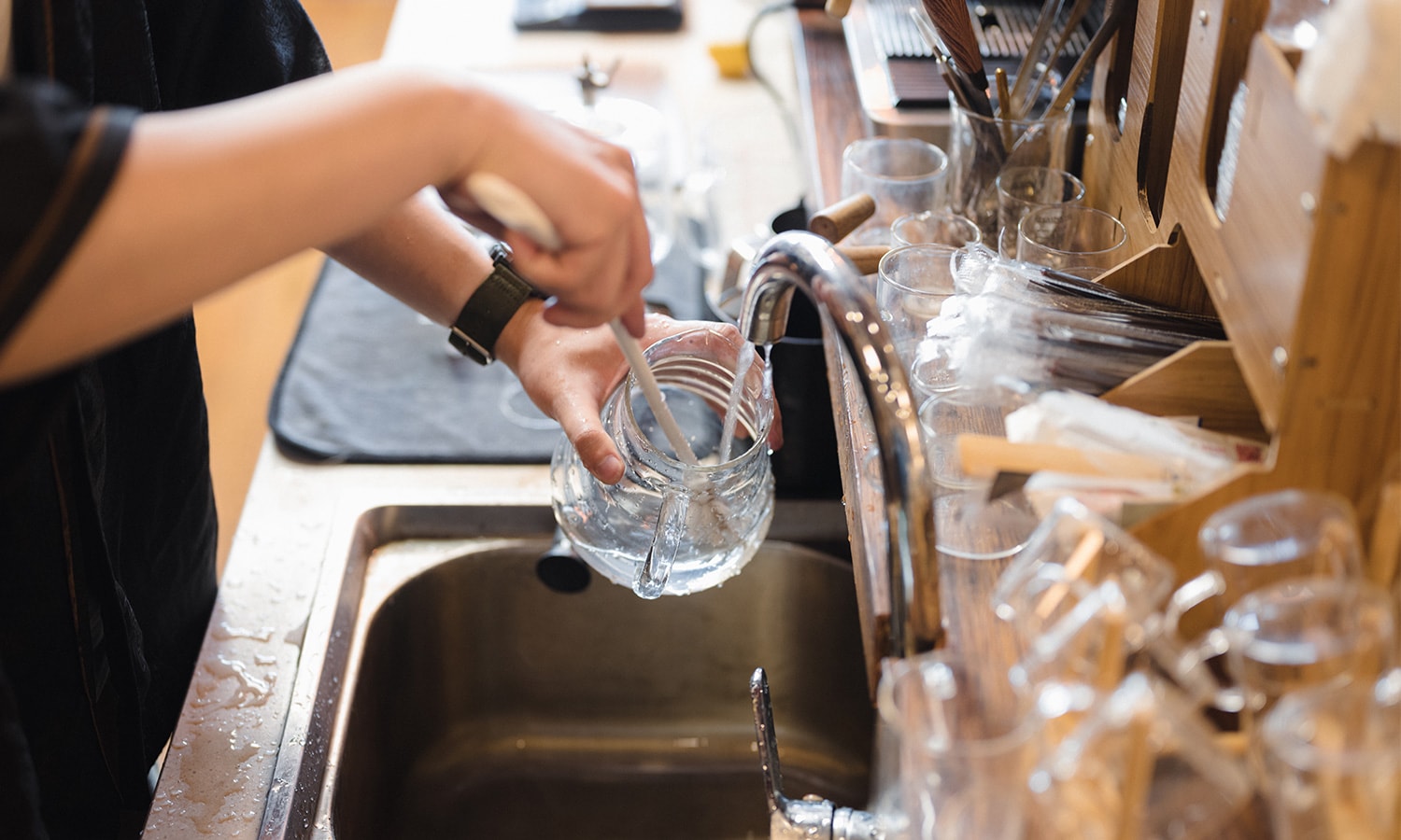 Frauenhände waschen ein ein Glas im Waschbecken ab