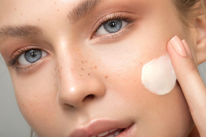 Gesichtspflege Nachtpflege Kategoriebild Frau cremt mit einem Finger weiße creme auf die Wange